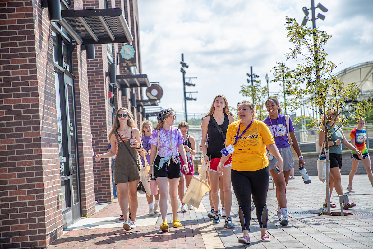 A group of students walking by storefronts in downtown Cedar Falls